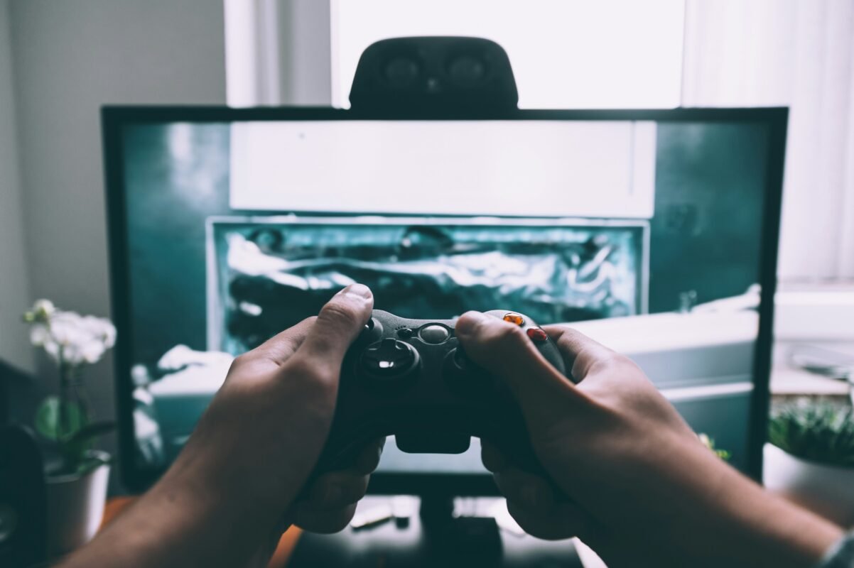 человек держит игровой контроллер перед телевизором