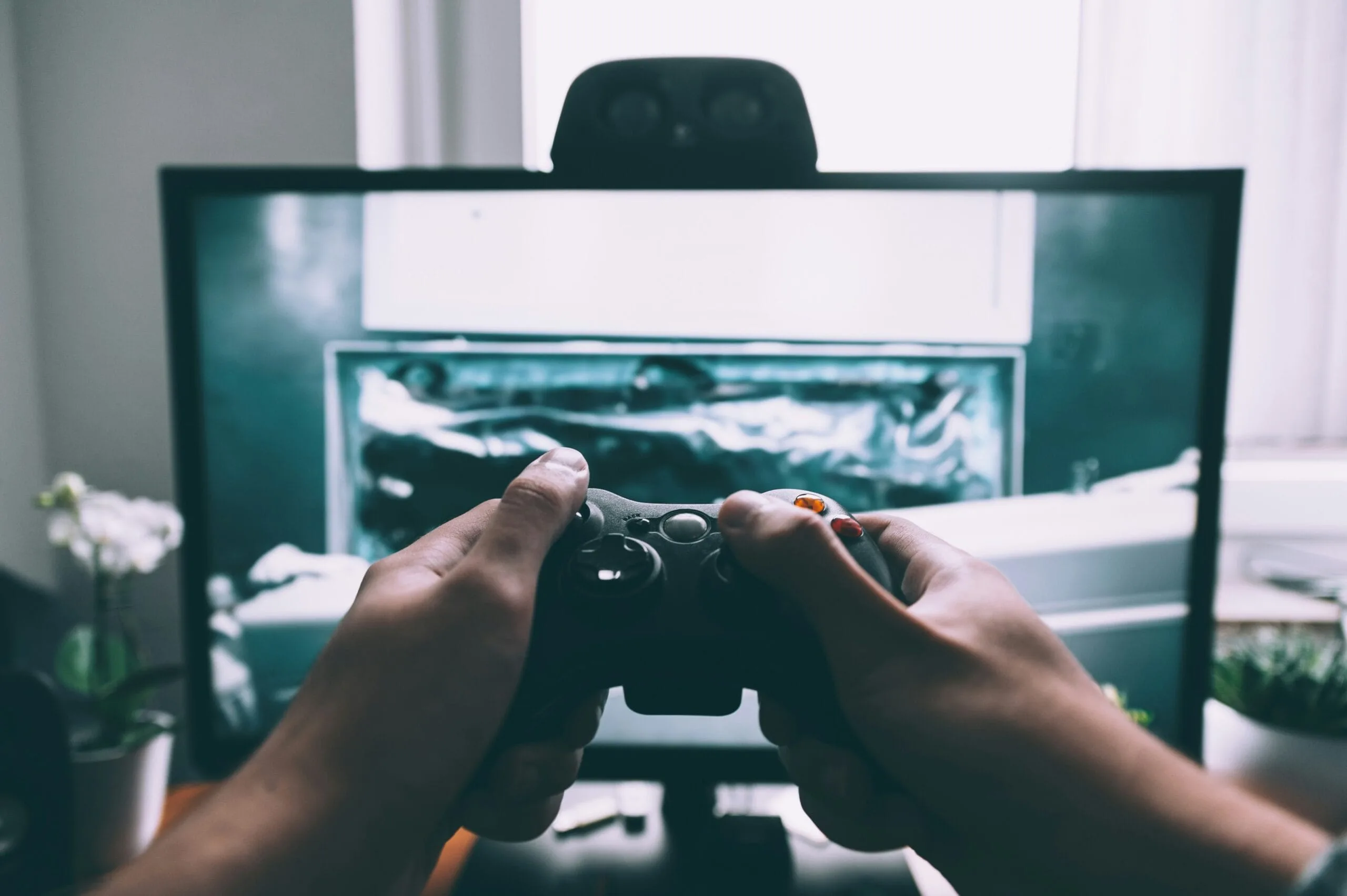 человек держит игровой контроллер перед телевизором